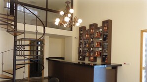Een modern interieur met een spiltrap, een bar met flessenkasten en een kroonluchter.