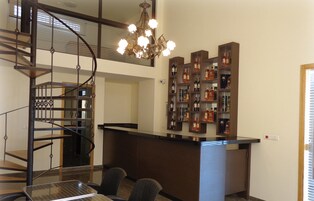 Un interior moderno con una escalera de caracol, una zona de bar con estantes llenos de botellas y una araña.