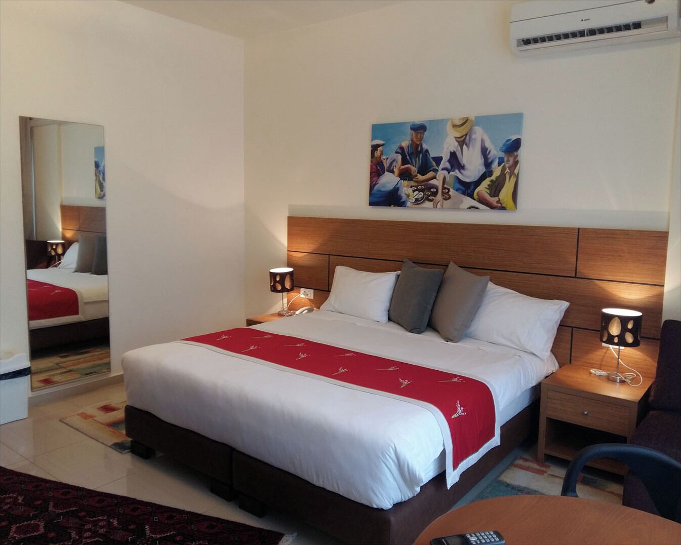 Een hotelkamer met een groot bed, twee nachtkastjes, een stoel en een schilderij aan de muur.