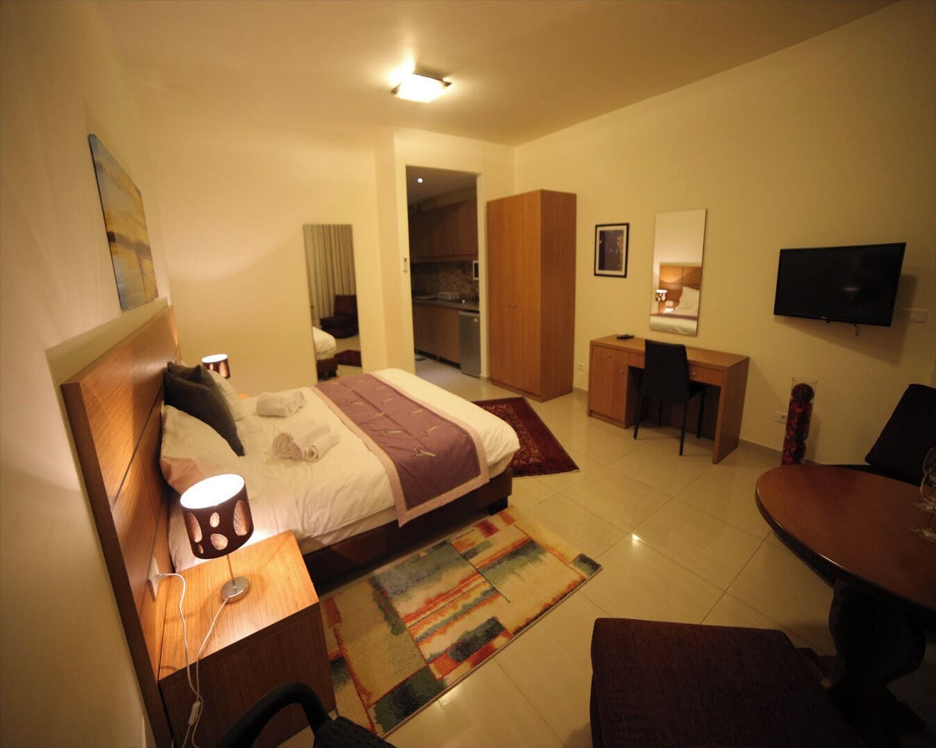 Een hotelkamer met een bed, bureau, stoel, televisie en een eettafel.