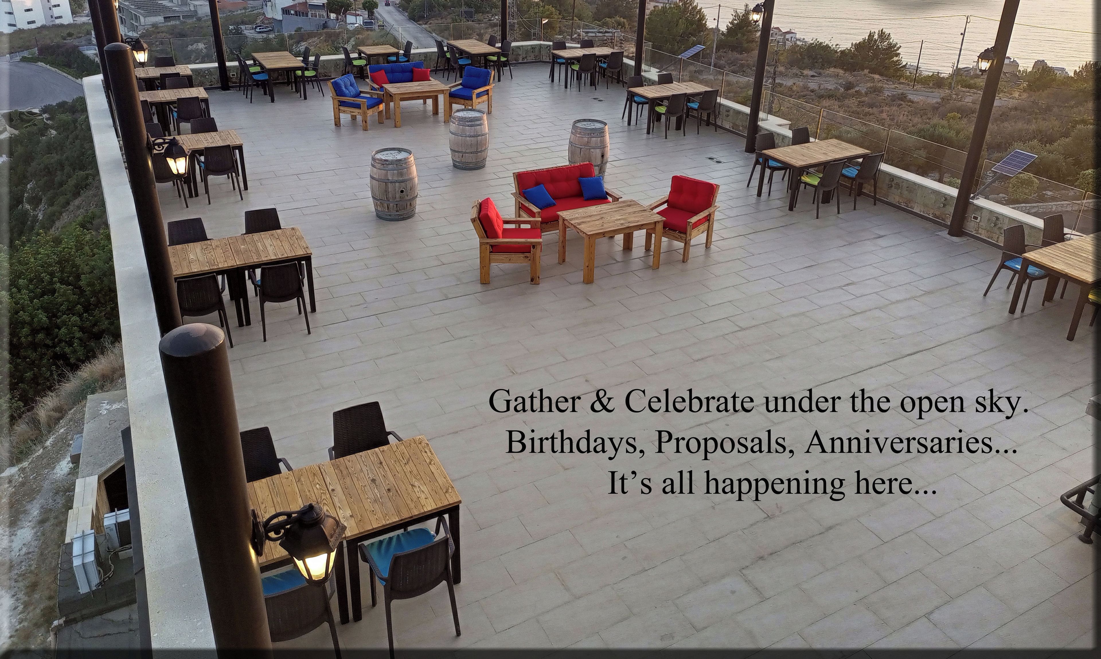 An outdoor seating area with tables and chairs, overlooking a coastal view.