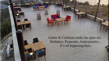 An outdoor seating area with tables and chairs, overlooking a coastal view.