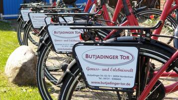 Rivi punaisia polkupyöriä, joissa on valkoiset kyltit, joissa lukee ”BUTJADINGER TOR” ja yhteystiedot.