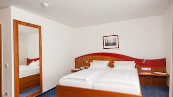 Habitación de hotel con una cama de madera, un escritorio con una silla, un espejo y un cuadro en la pared.