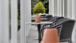 A row of outdoor tables and chairs with a central planter.