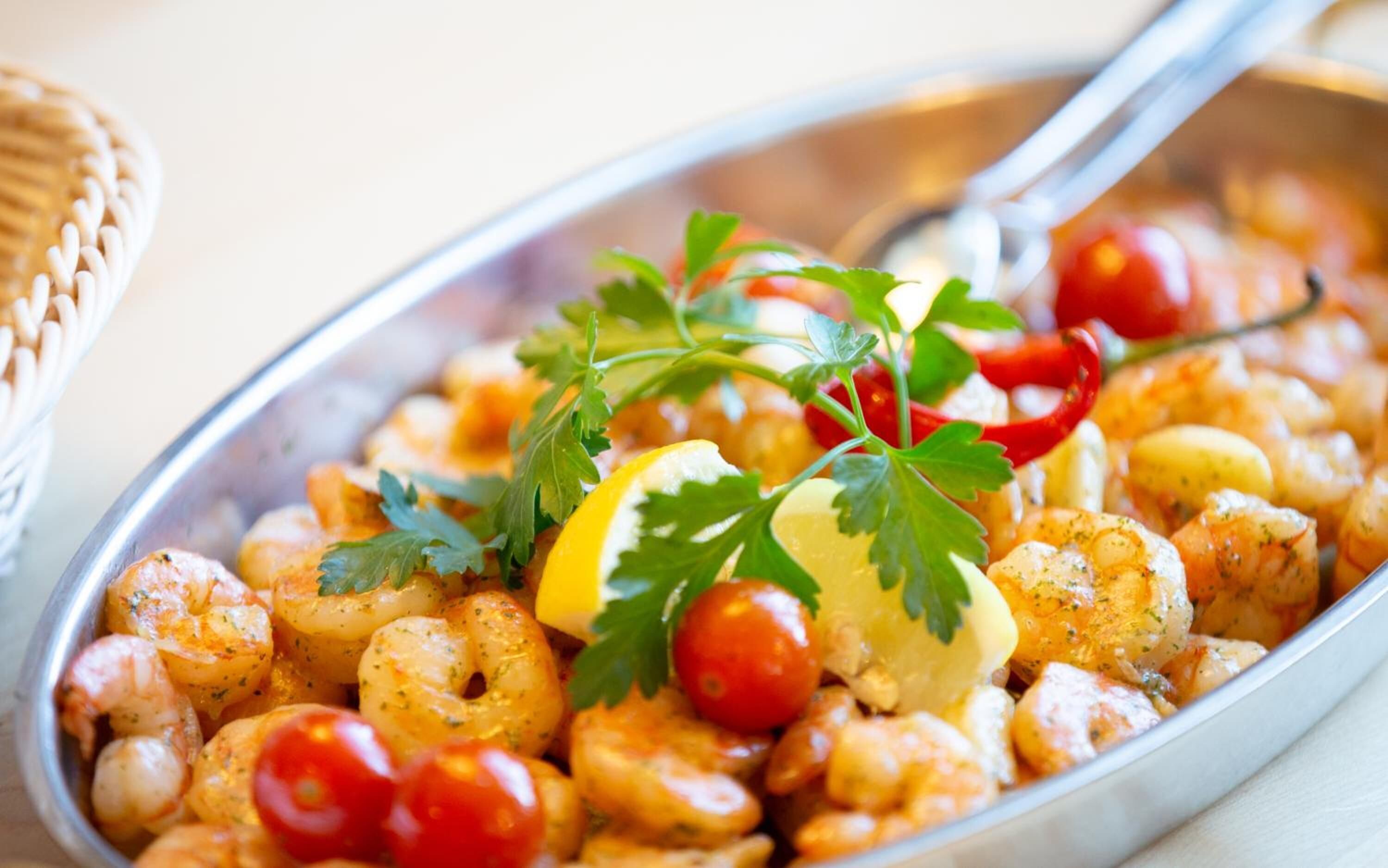 A dish of shrimp with lemon, parsley, and cherry tomatoes.