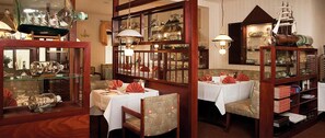 A dining area with tables set for two, surrounded by glass display cases containing various items.