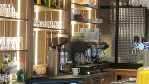A bar area with shelves of liquor bottles, glasses, and a coffee machine. - Hotel Le Faisan (Saint-Avertin)