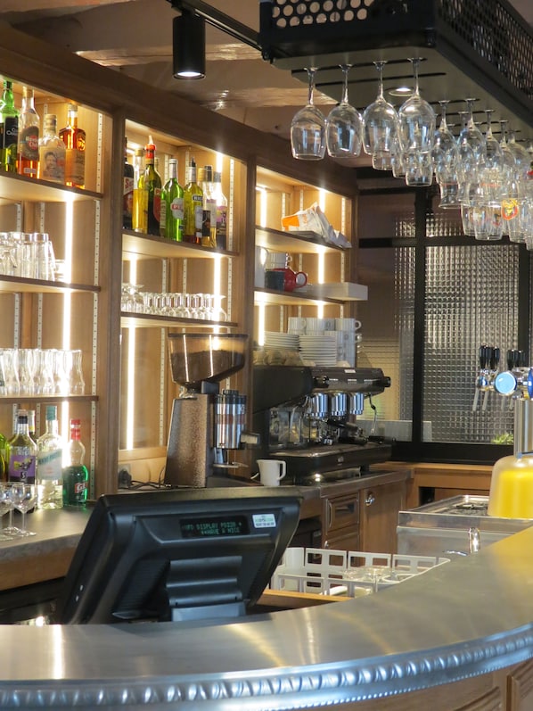A bar area with shelves of liquor bottles, glasses, and a coffee machine.
