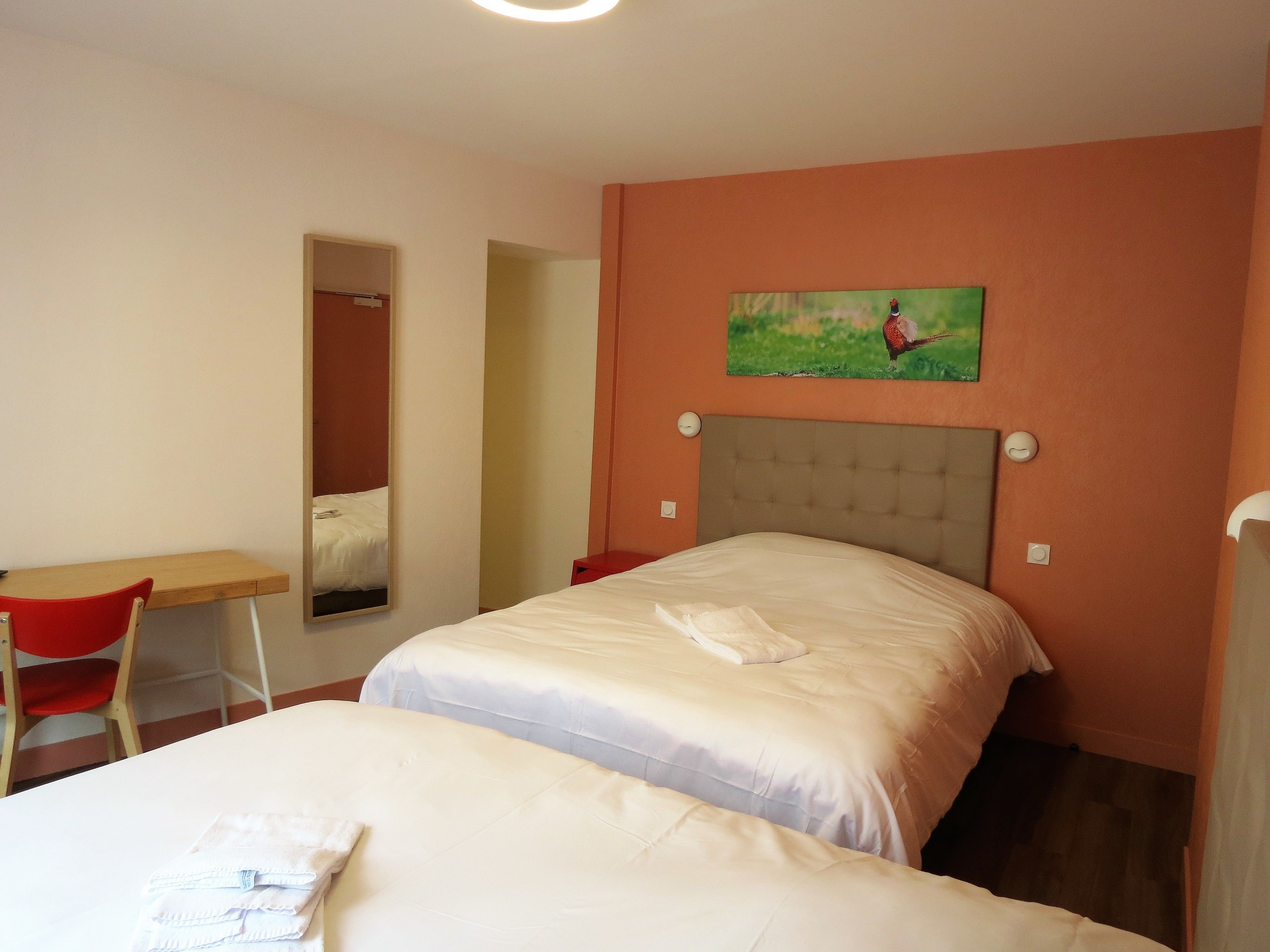 Una habitación de hotel con una cama, un escritorio y una silla.