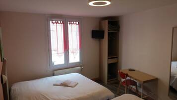 Habitación de hotel con dos camas, un escritorio, una silla, un armario y un televisor montado en la pared.