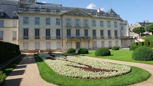 A large, historic building with symmetrical architecture, a central courtyard with a geometric flower bed, and a well-maintained lawn. - Hotel Le Faisan (Saint-Avertin)