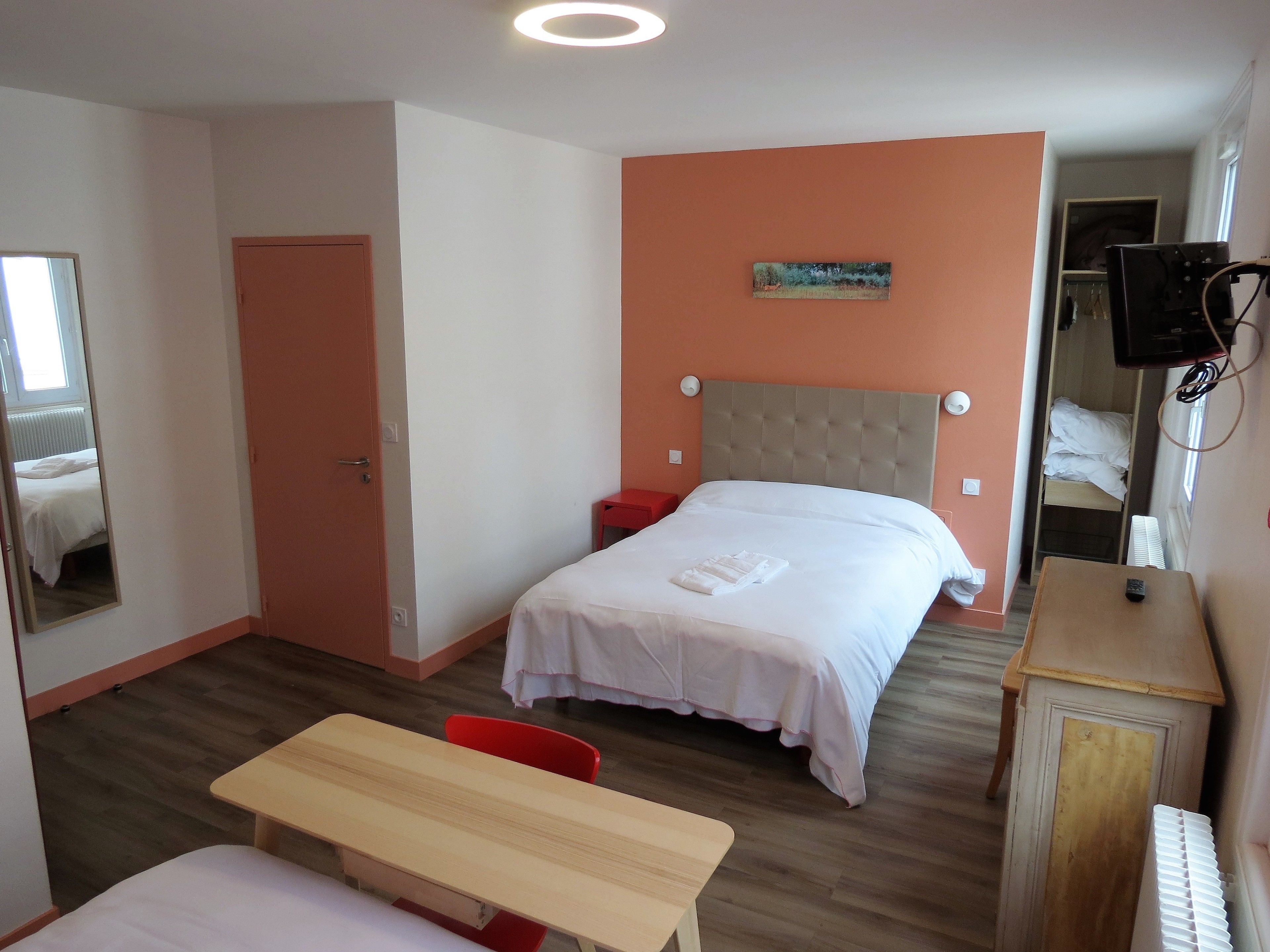 Una habitación de hotel con una cama, un escritorio, una silla, un televisor y una ventana.