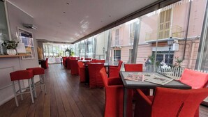 A restaurant with red chairs and tables, large windows, and a wooden floor. - Hotel Aida (Alassio)