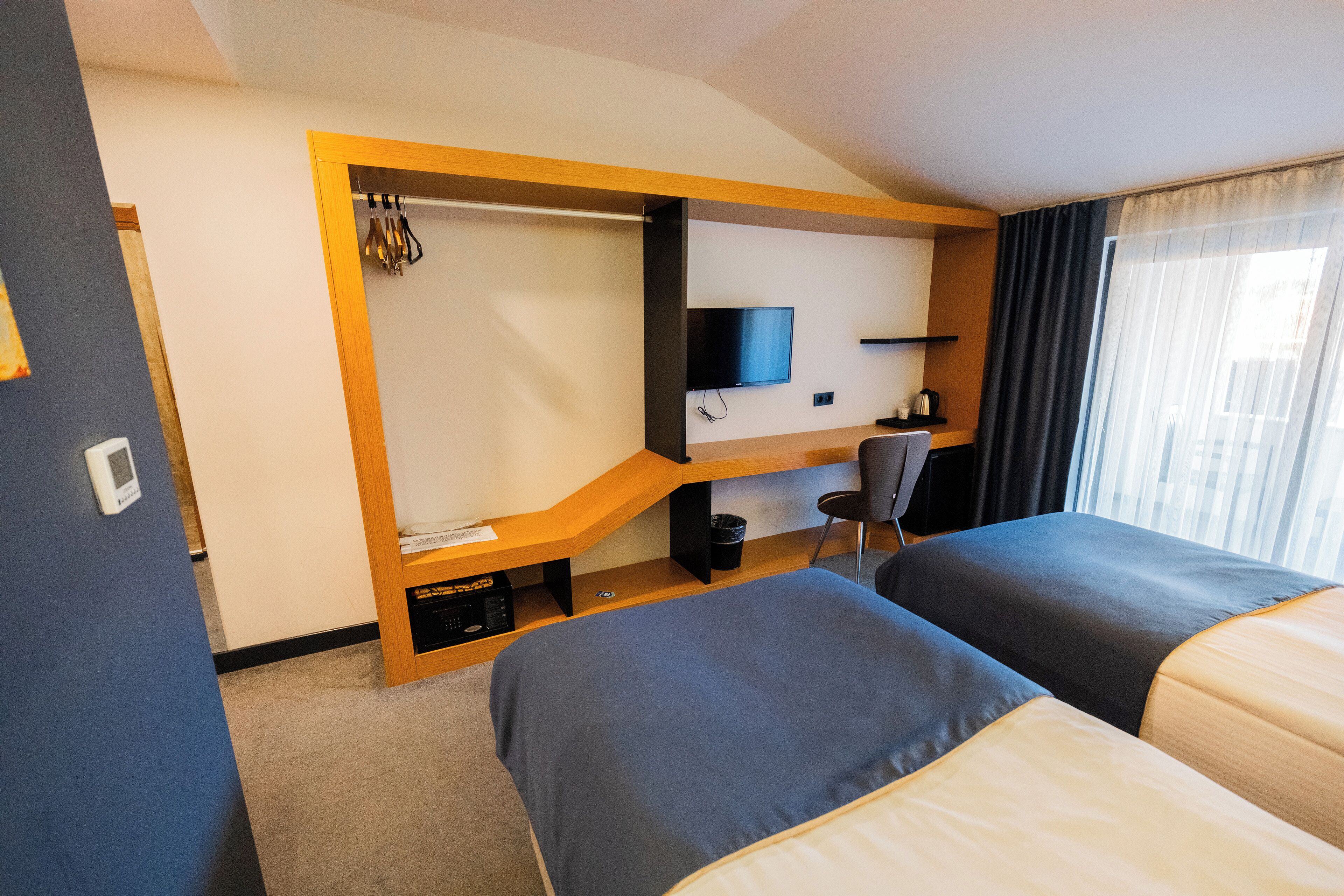 A hotel room with two beds, a TV, a desk, and a chair.