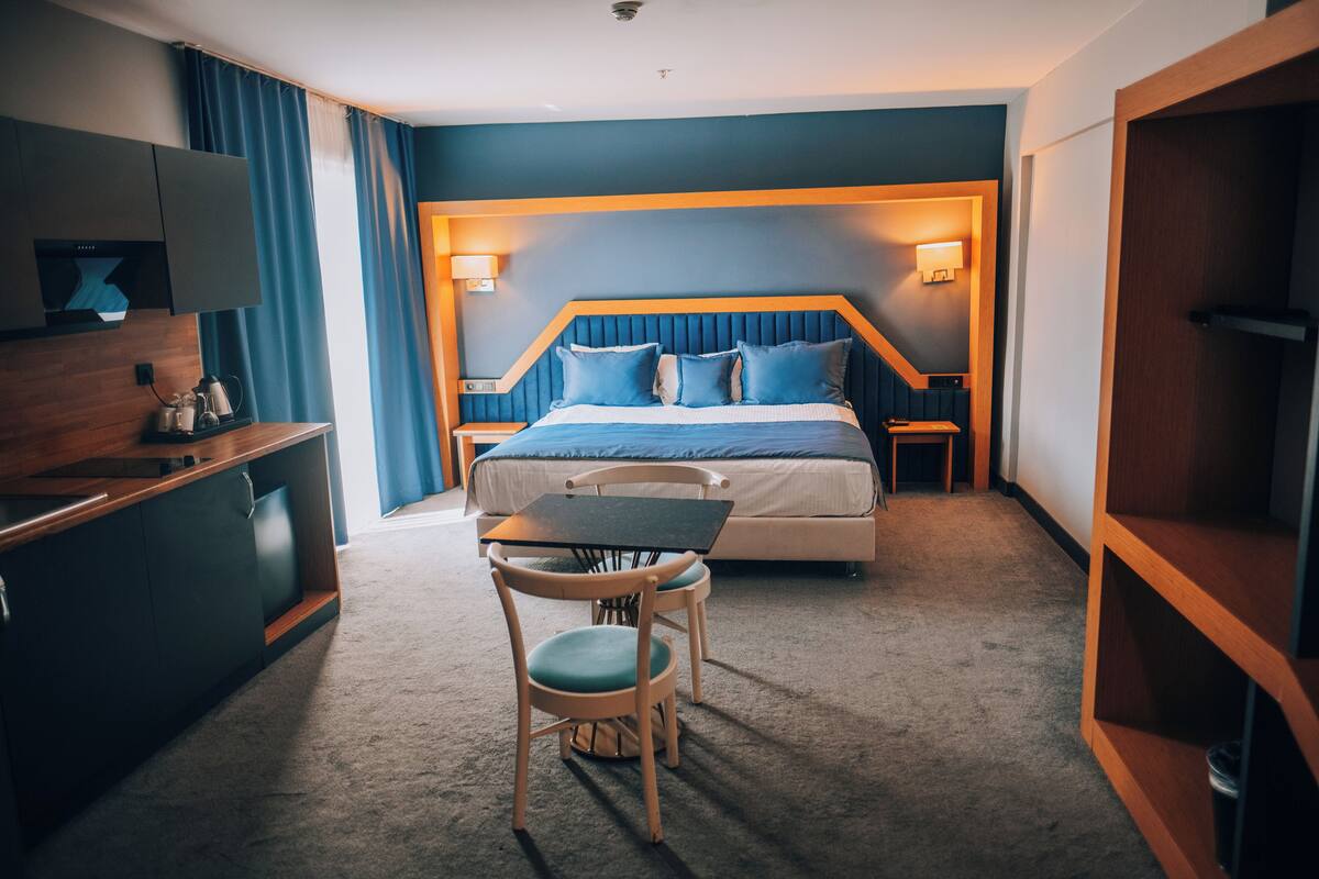 Une chambre d’hôtel équipée d’un lit, d’un bureau, d’une chaise, d’une télévision et d’une kitchenette.