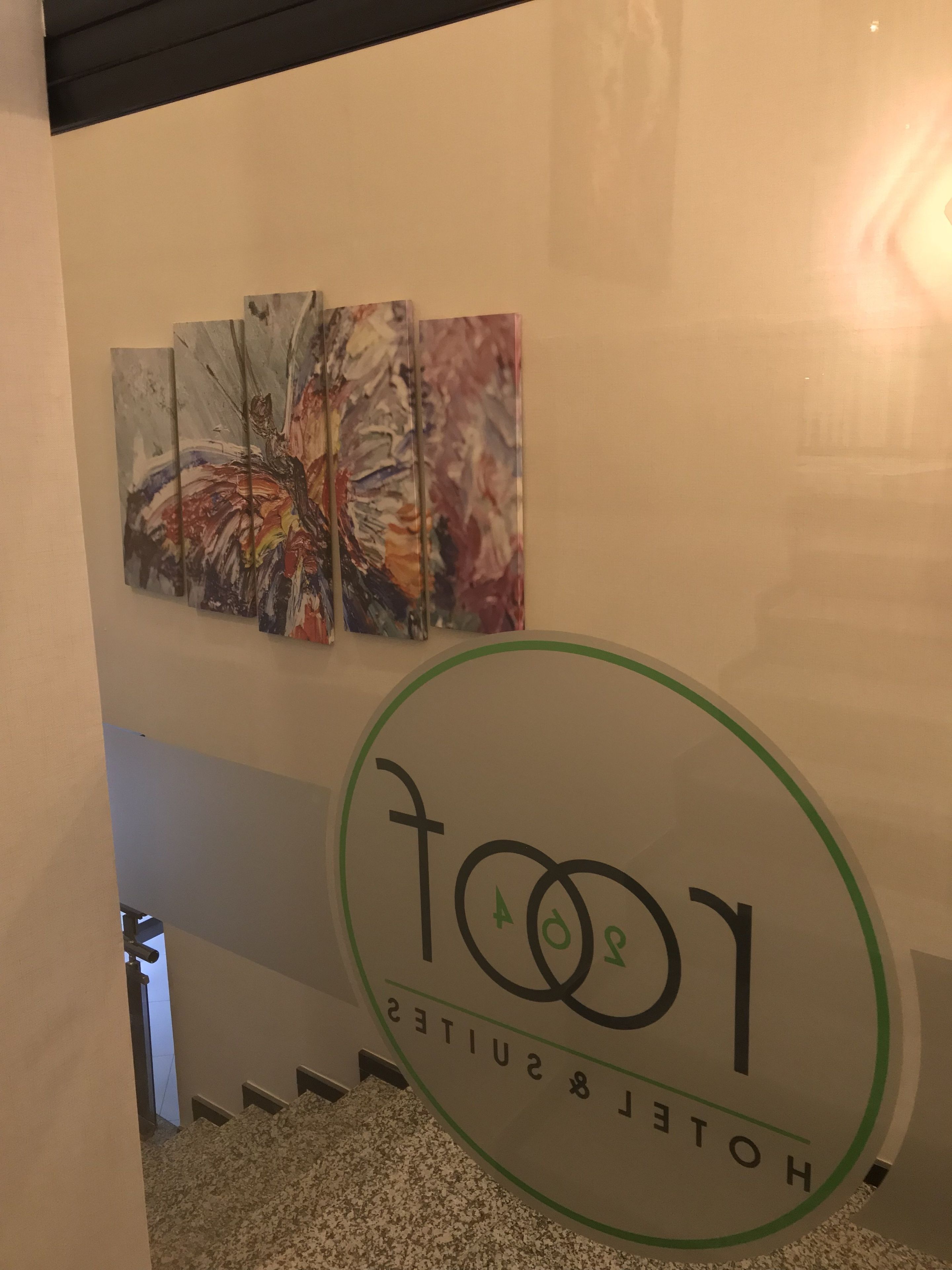 A hotel sign with the name 'Hotel & Suites' and a logo. There are three paintings on the wall above the sign.
