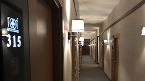 A hotel corridor with doors numbered 315, featuring overhead lighting and a carpeted floor.