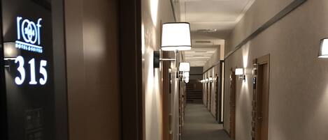 A hotel corridor with doors numbered 315, featuring overhead lighting and a carpeted floor.