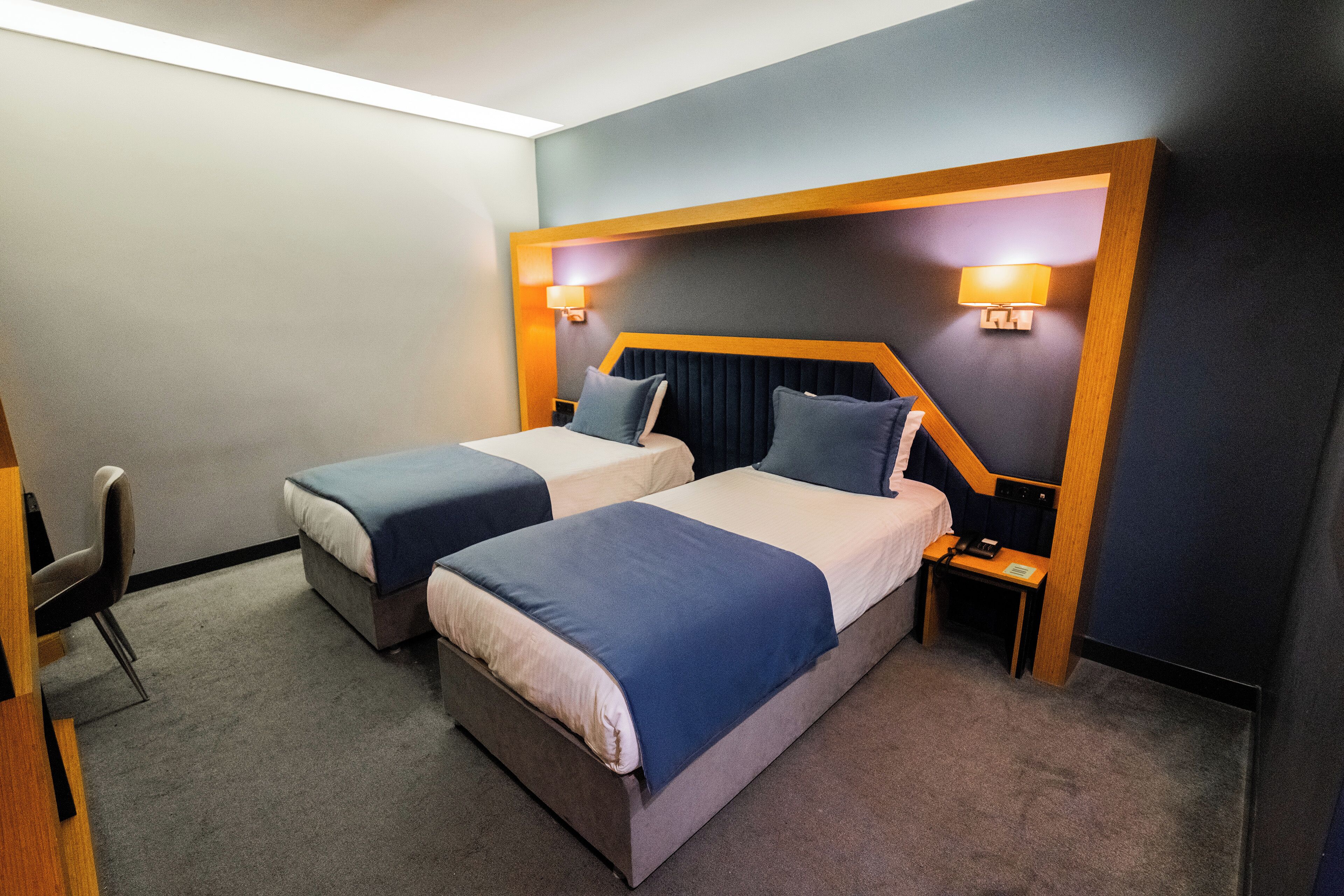 Ein Hotelzimmer mit zwei Betten, einem Schreibtisch und einem Stuhl.