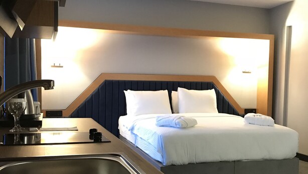 A hotel room with a bed, bedside table, and a built-in sink.