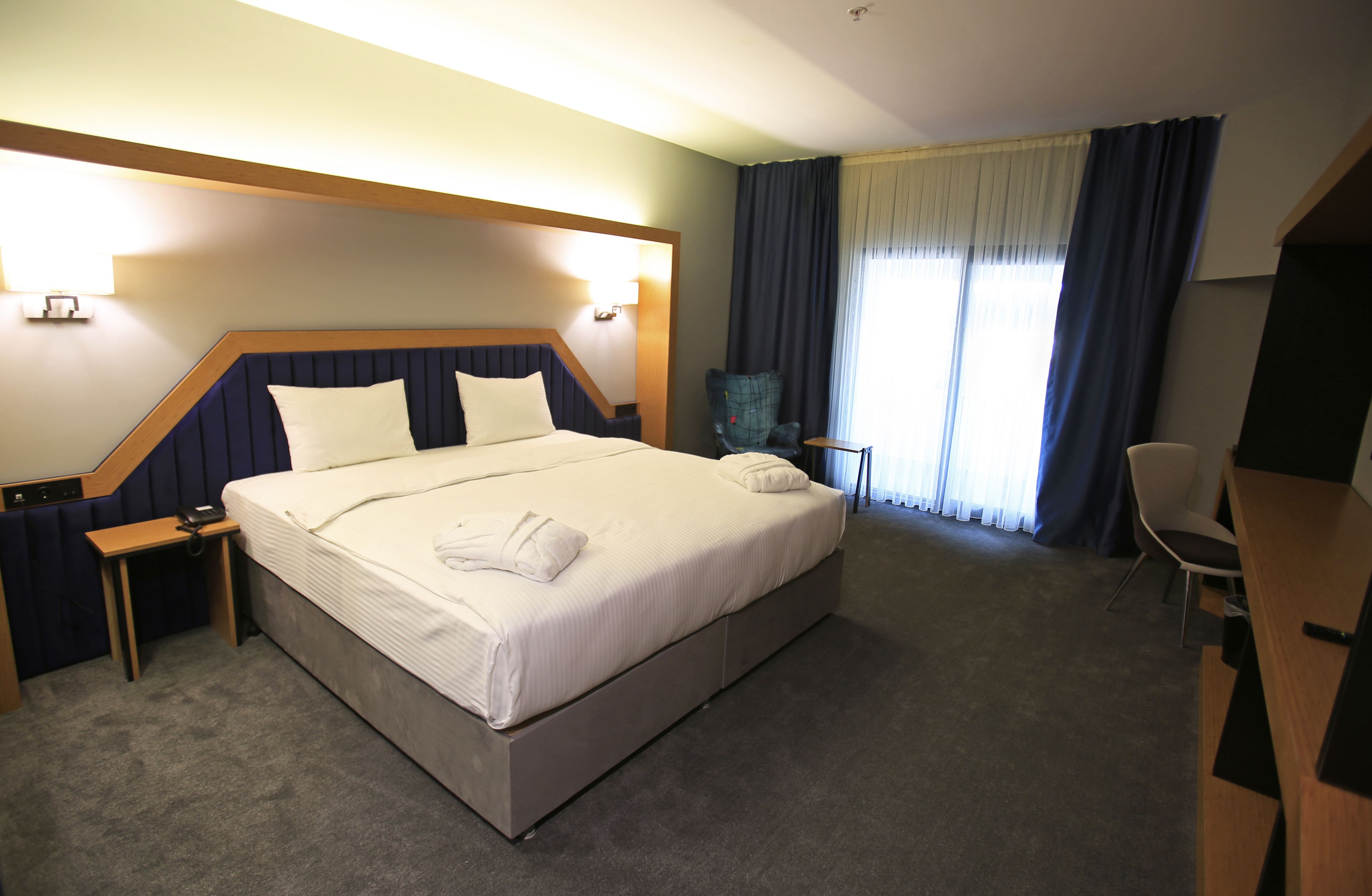 Una habitación de hotel con una cama grande, mesitas de noche, un escritorio y una silla.