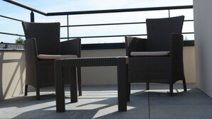 A balcony with two wicker chairs and a small table, featuring a clear view of the sky. - Brit Hotel Confort Loches (Loches)