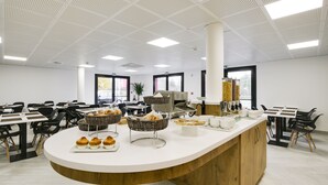A modern kitchen area with a central island, various kitchen appliances, and seating arrangements. - Brit Hotel Confort Loches (Loches)