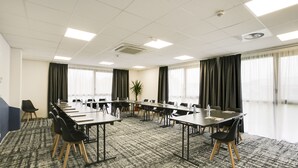A conference room with a long table, chairs, and a carpeted floor. - Brit Hotel Confort Loches (Loches)