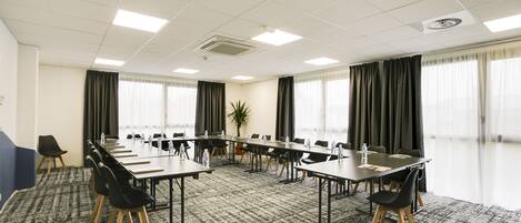 A conference room with a long table, chairs, and a carpeted floor.