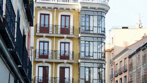 Un edificio de varios pisos con balcones, un restaurante llamado 'Chocolate y Churros' y mesas al aire libre.
