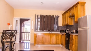 Una cocina moderna con armarios de madera, un refrigerador de acero inoxidable y un comedor con mesa y sillas.