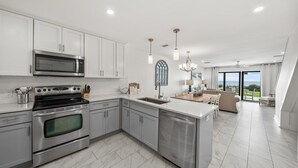 A modern kitchen with stainless steel appliances, a central island, and a view to the outdoors. - Seacrest - 6 - 2 Br townhouse by RedAwning (Panama City Beach)