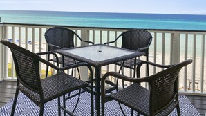 Ein Balkon mit Tisch und Stühlen mit Blick auf einen Strand.