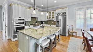 A spacious kitchen with a large island, built-in appliances, and a dining area with wooden chairs.