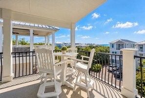 A balcony with white furniture and a view of the ocean and neighboring houses. - Pompano Palace - 4 Br home by RedAwning (Panama City Beach)
