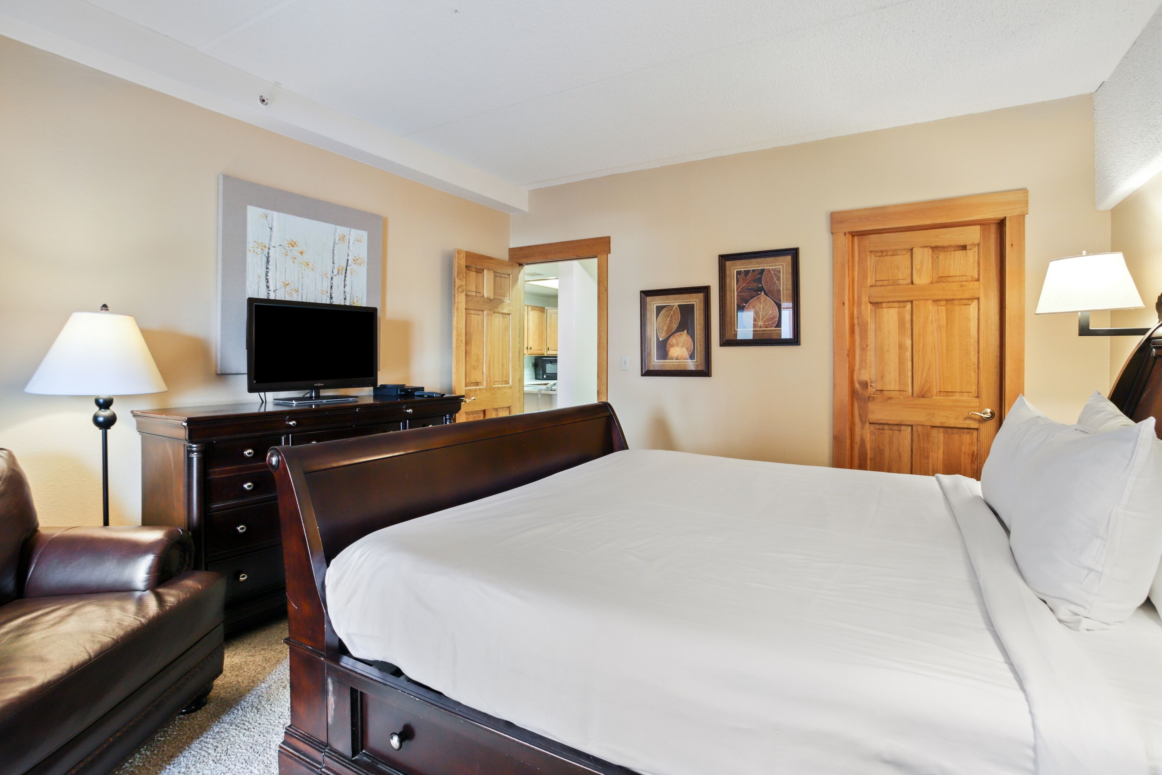 A hotel room with a large bed, a TV, a desk, and a chair.