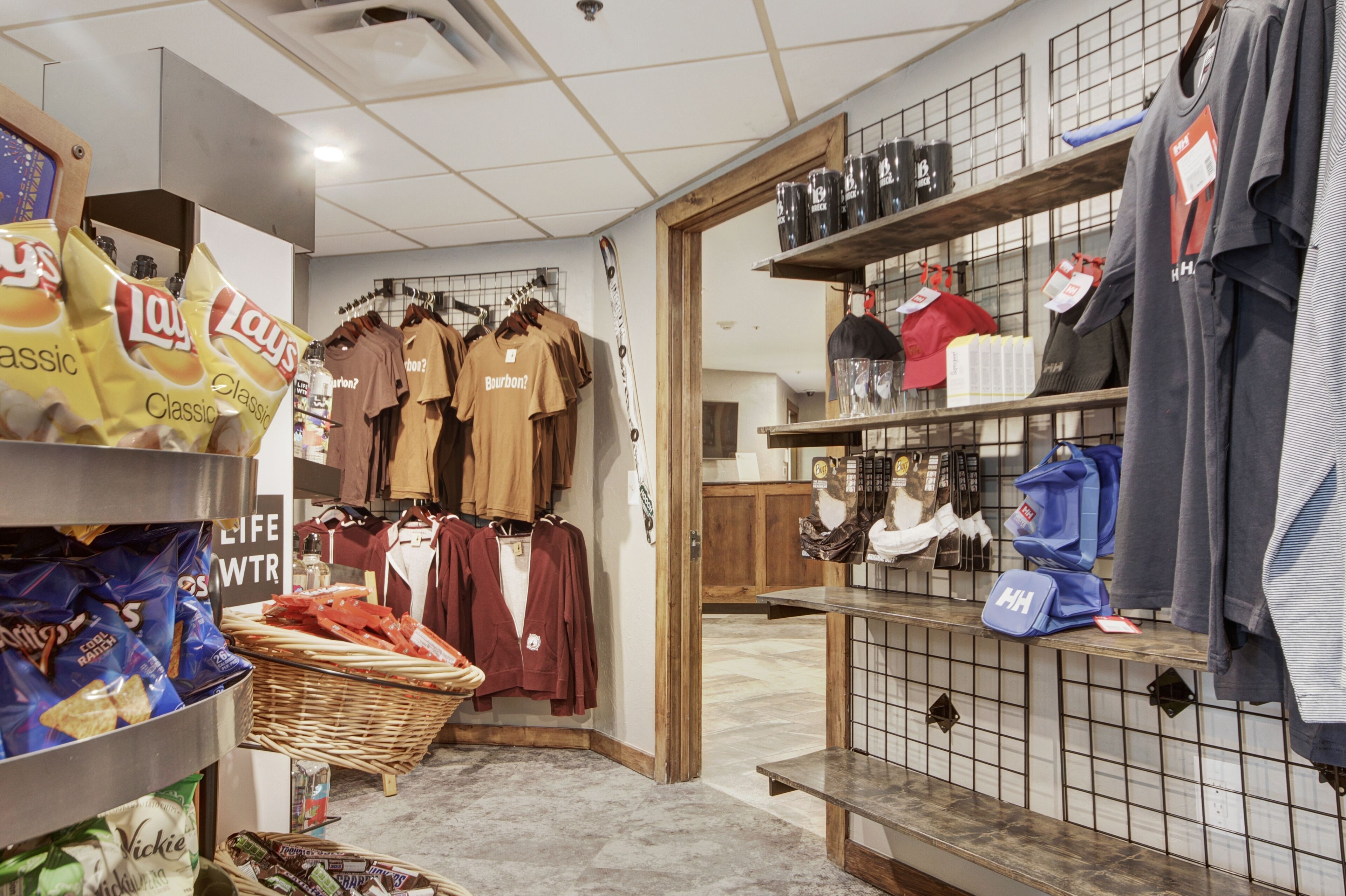 A retail store with snack bags, clothing racks, and shelves with various items.