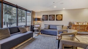 A modern living room with a grey sofa, a round coffee table, and a wooden cabinet. - Stay Slopeside At Peak 9, Cozy Studio Steps To Apres& Dining Studio Bedroom Condo by RedAwning (Breckenridge)
