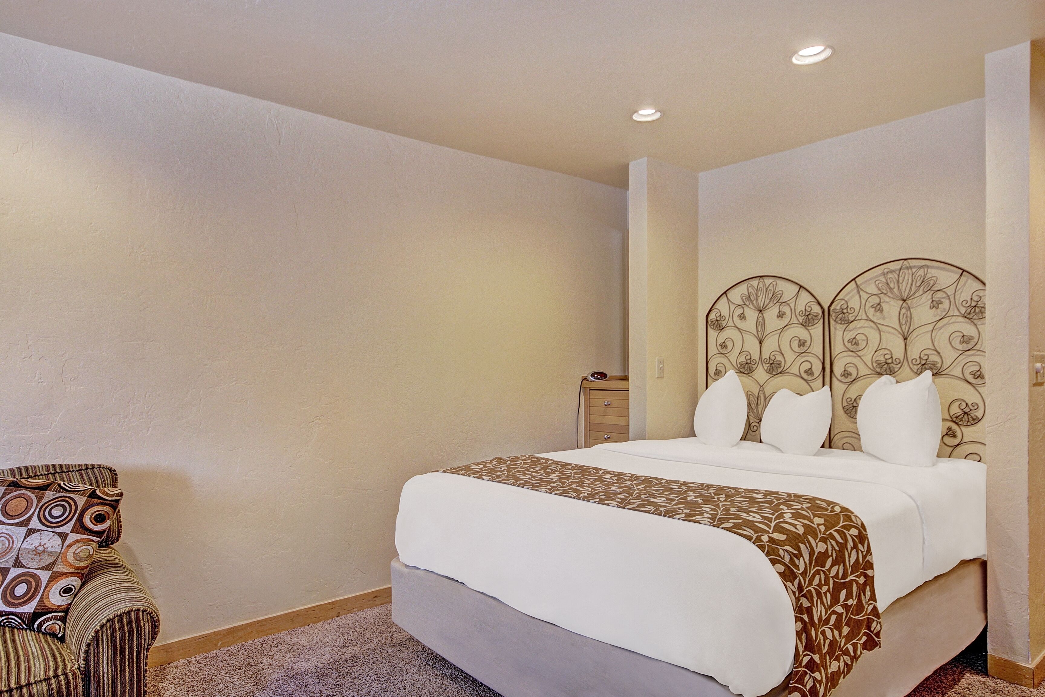 A hotel room with a large bed, a chair, and a nightstand.