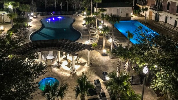 A pool area with two pools, lounge chairs, and a covered seating area.