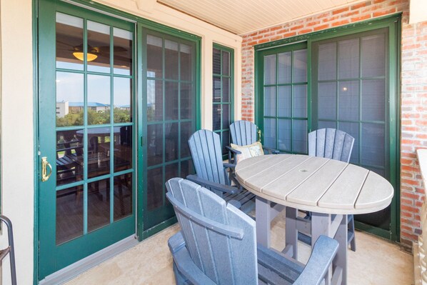 Un patio con una mesa redonda y seis sillas Adirondack.