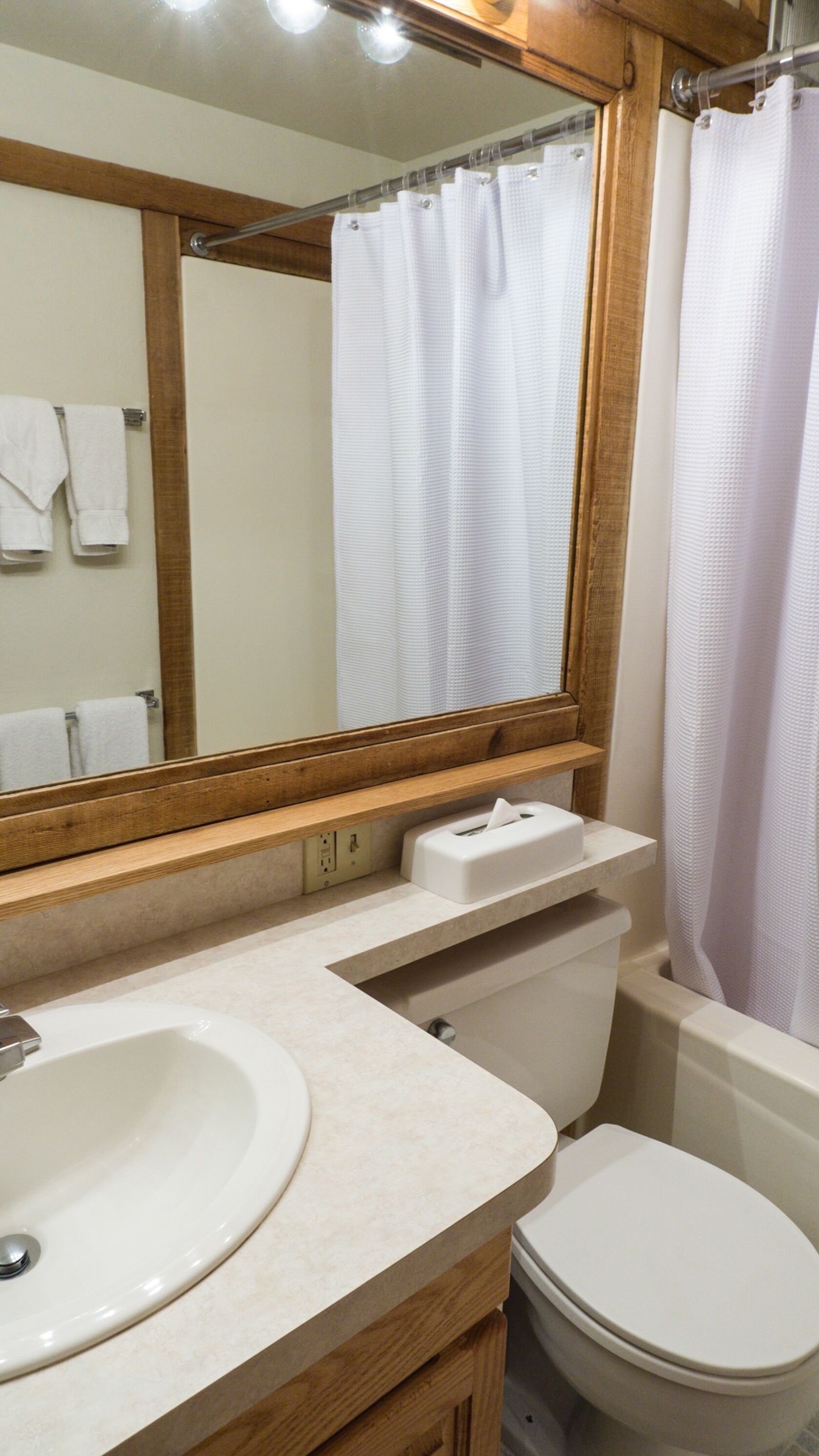 A bathroom with a sink, mirror, toilet, and shower curtain.