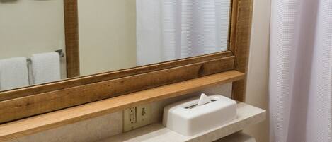 A bathroom with a sink, mirror, toilet, and shower curtain.