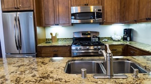A kitchen with stainless steel appliances, granite countertops, and wooden cabinets. - Ski Trails 4058 (Truckee)