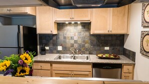 A modern kitchen with granite countertops, a double sink, and wooden cabinets. - Ski Trails 4113 (Truckee)