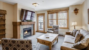 Un salón con chimenea, sofá, sillón y televisión.