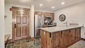 A kitchen with wooden cabinets, stainless steel appliances, a white countertop, and a tiled floor. - Refined  With Sunny Views 2 Blocks To Downtown Breck 1 Bedroom Condo by RedAwning (Breckenridge)