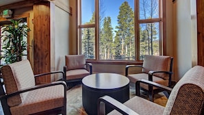 A room with large windows, wooden furniture, and a view of trees. - Refined  With Sunny Views 2 Blocks To Downtown Breck 1 Bedroom Condo by RedAwning (Breckenridge)