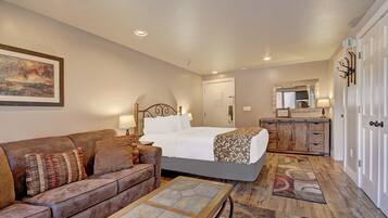 Quarto de hotel com cama, sofá, mesa de centro, cômoda e espelho.